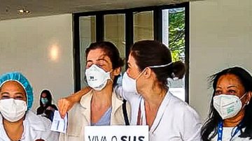 Emocionada, Renata Vasconcellos se vacina ao lado da irmã gêmea e leva cartaz de protesto - AgNews