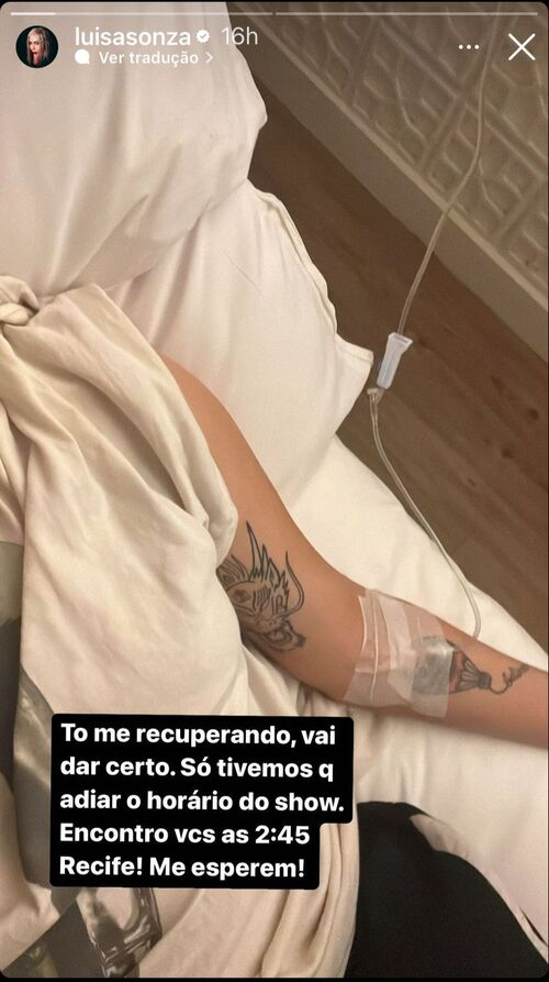 Foto do braço de Luísa Sonza com uma agulha injetada na aveia, enquanto recebe medicamento. Na imagem, é possível ver a bolsa da medicação, na legenda, ela explica que está se recuperando para realizar o show