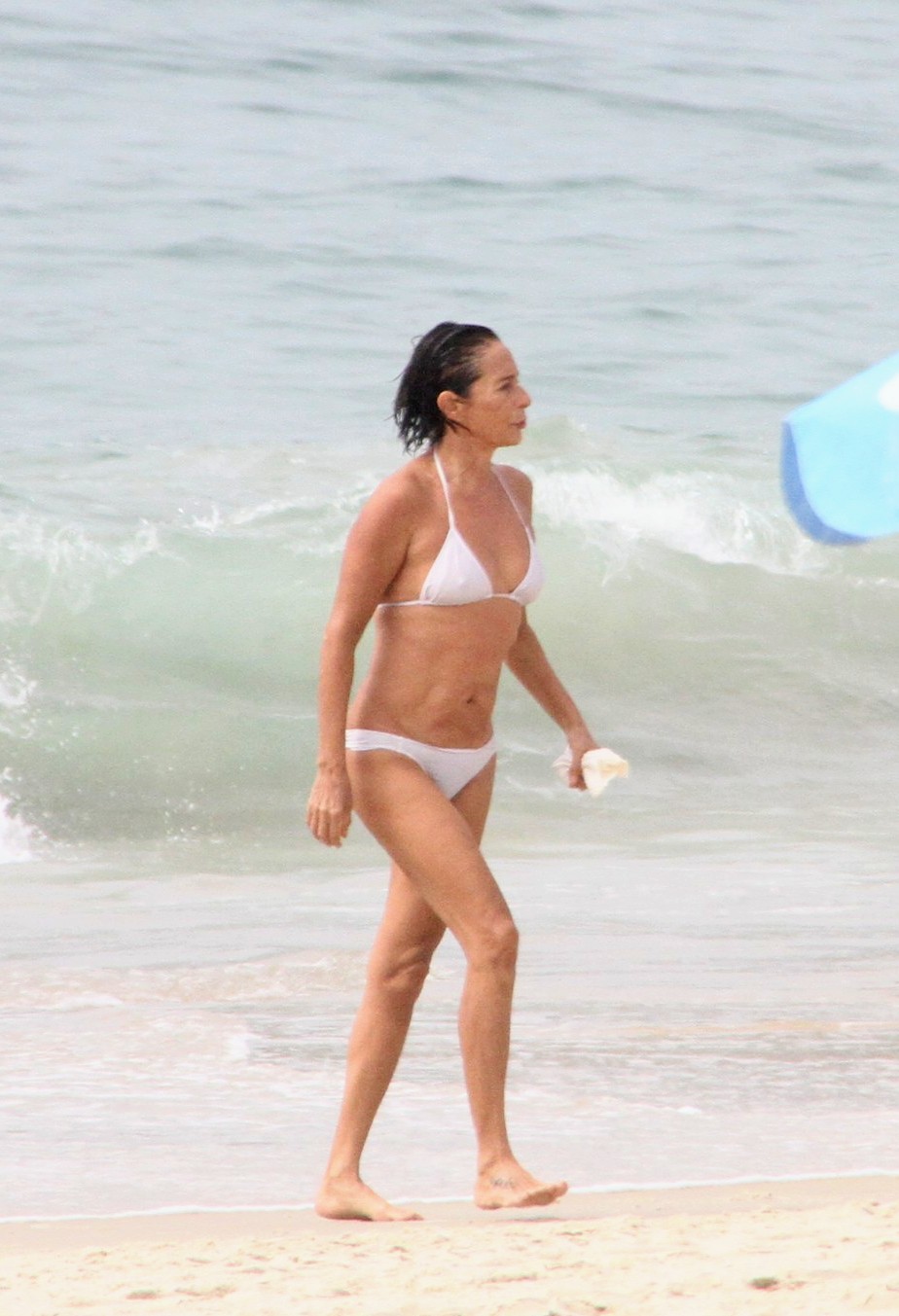 Foto de Andréa Beltrão andando na praia de biquíni branco
