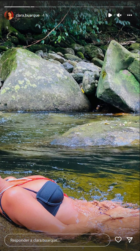 Foto de Clara Buarque retirada dos Stories do Instagram, sem mostrar o rosto, de biquíni em um rio
