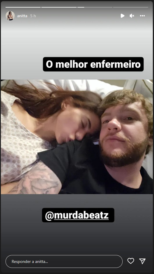 Foto de Anitta, usando um avental de hospital, beijando o ombro do namorado, Murda Beatz, ambos deitados em uma cama de hospital, com os dizeres: "O melhor enfermeiro"