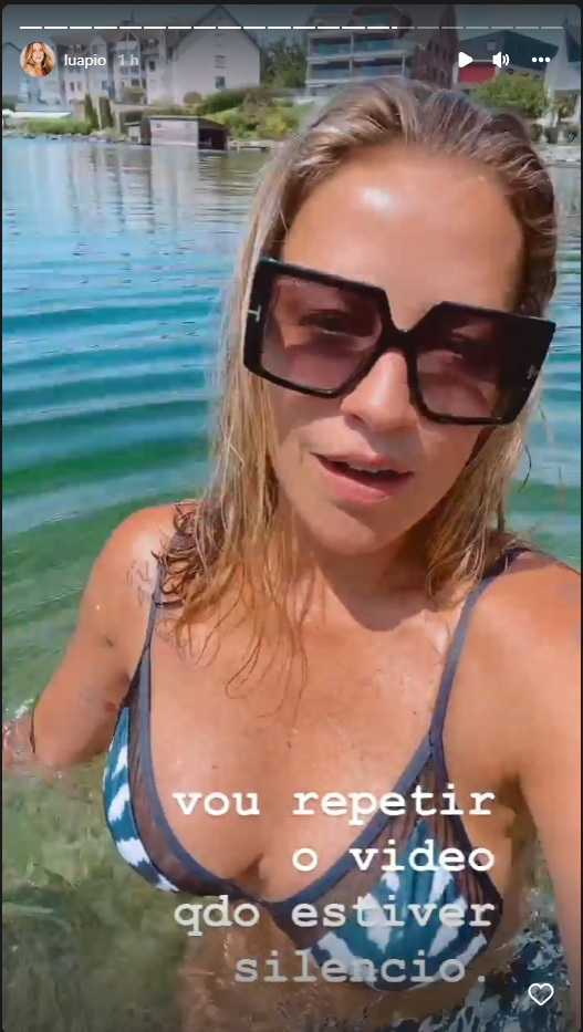 Foto de Luana Piovani de biquíni em um lago na Suíça, de óculos escuros, com os dizeres: "Vou repetir o vídeo quando estiver silêncio"