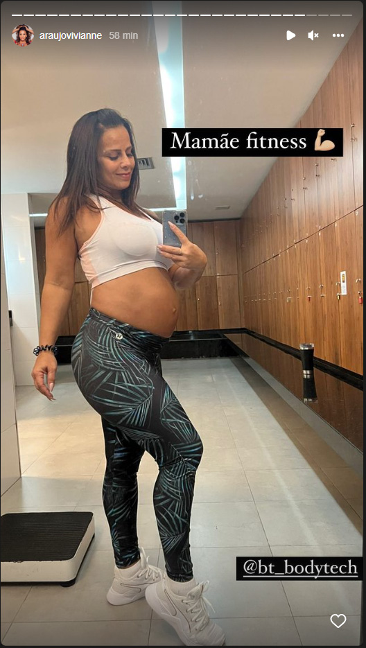 Viviane Araújo posando de top e calça legging na academia, mostrando barriga de grávida com os dizeres: "Mamãe fitness"