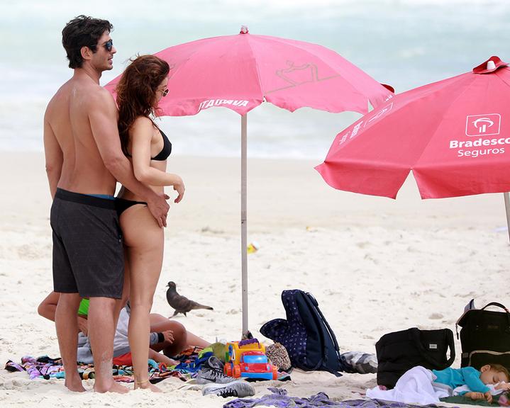 Isis Valverde troca carícias com marido na praia