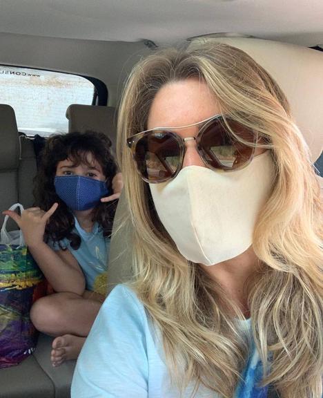 Letícia Spiller surge com a filha de máscara dentro do carro