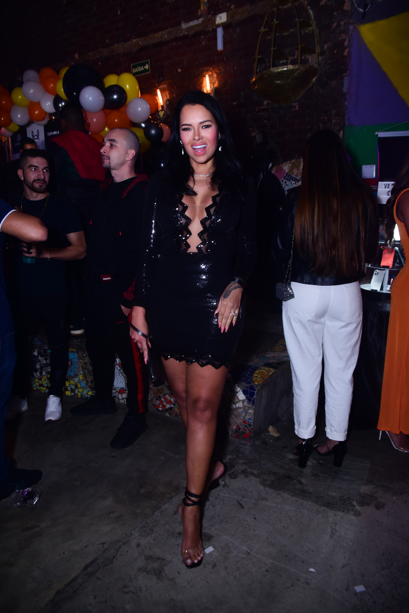 Foto de Ariadna Arantes com vestido preto e decotado em festa